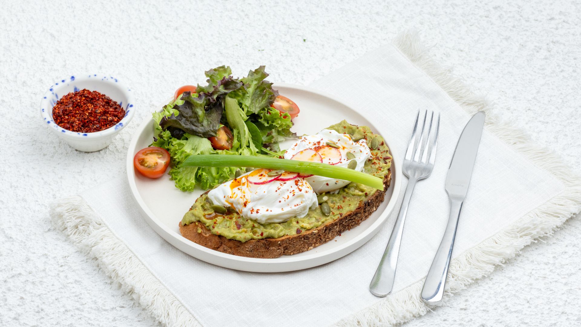 Avocado toast with poached eggs, chilli flakes and salad